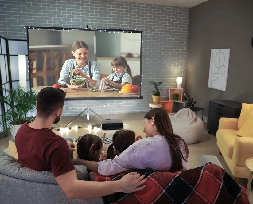 A family relaxing on couches, engaged in watching a movie on a TV