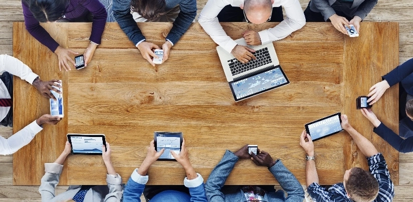 A group of people collaborating around a table, each using their laptops for a work session