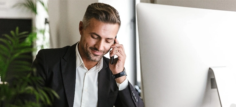 A man in a suit is talking on the phone, appearing engaged in a conversation