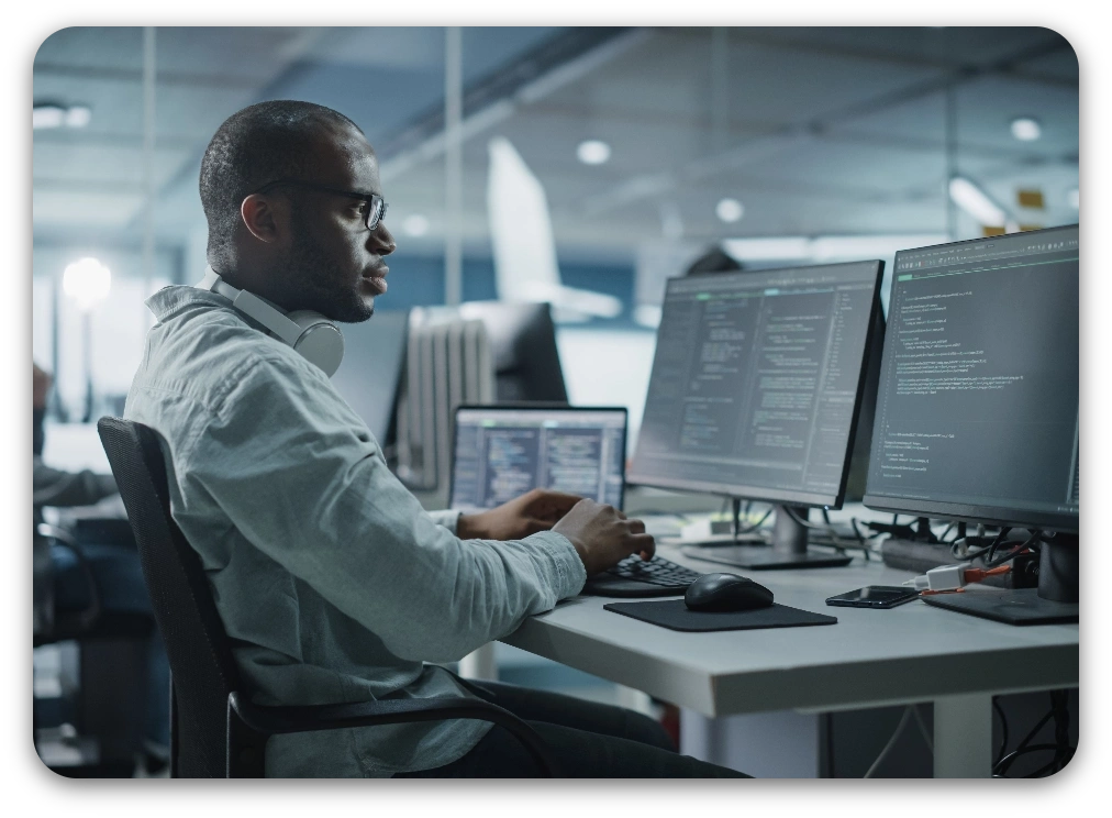 A man sitting at a desk with two computers