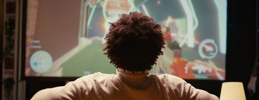 A person sitting on a couch, focused on a TV screen