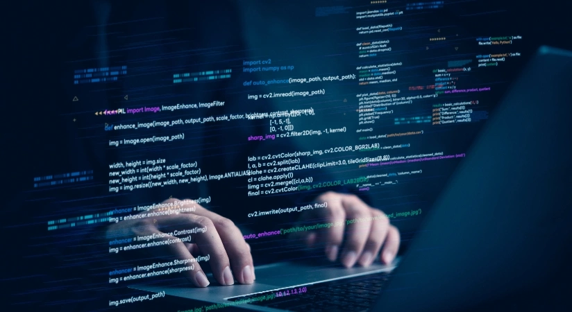 A person typing on a laptop, with lines of code displayed on the screen