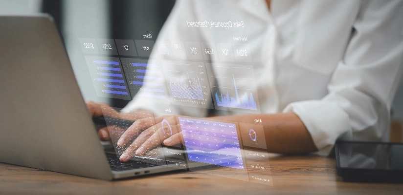 A person typing on a laptop, with the screen displaying various colorful graphs and data visualizations