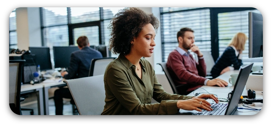 A woman focused on her laptop while working in a modern office environment