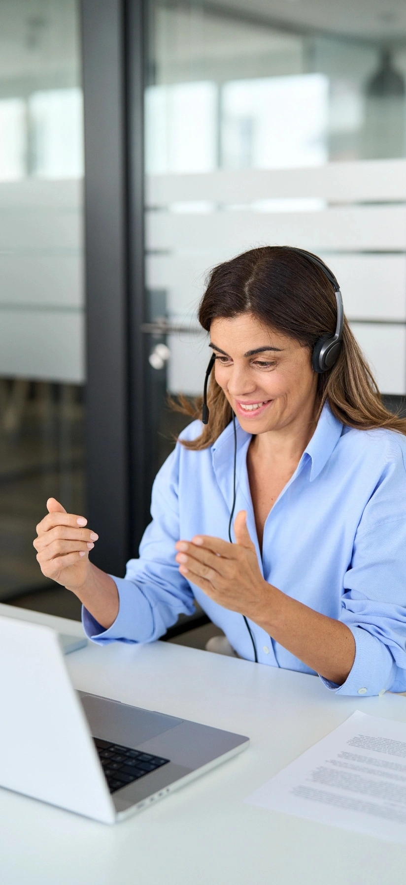 A woman with headphones and a headset is at her desk
