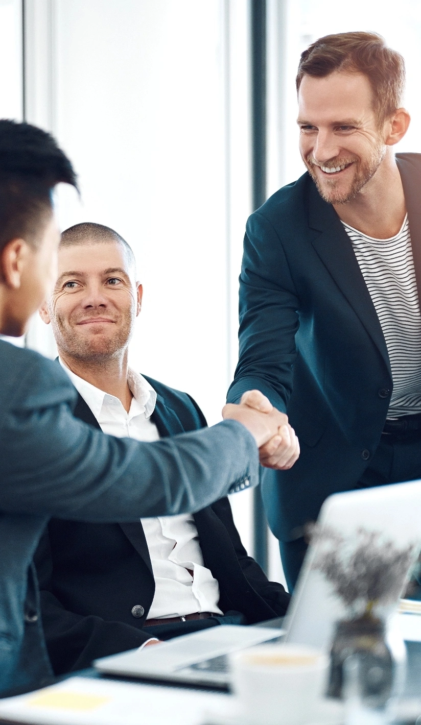 Three business men shaking hands in a modern office setting