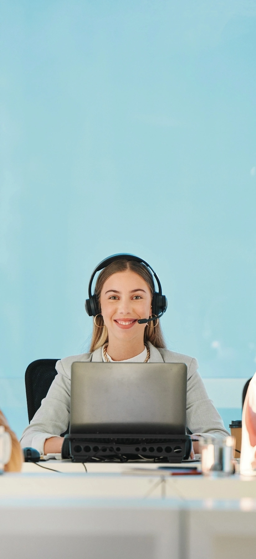 woman in headphones sits at a desk, using a laptop